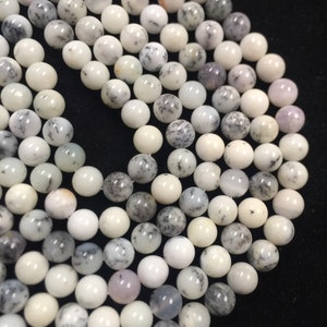 May include: A strand of white and gray dendritic opal beads. The beads are round and have a smooth, polished finish.