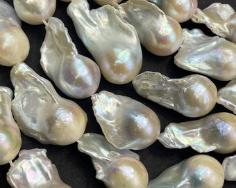 May include: A strand of large, irregular, white baroque pearls with iridescent hues. The pearls are strung together and have a natural, organic shape.