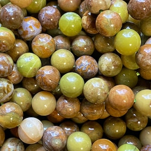 May include: A strand of green and brown opal beads. The beads are round and have a smooth, polished finish. They are perfect for making jewelry.