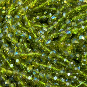 May include: A strand of green faceted glass beads with iridescent shimmer. The beads are strung on a clear thread.