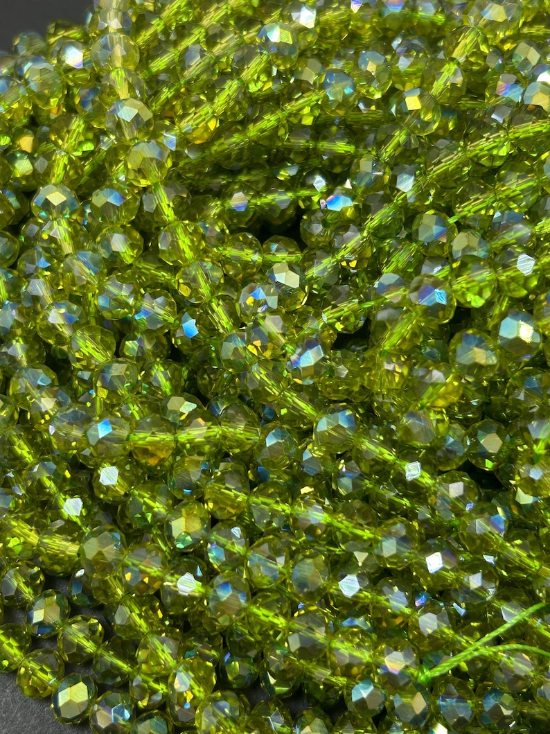 May include: A strand of green faceted glass beads with iridescent shimmer. The beads are strung on a clear thread.