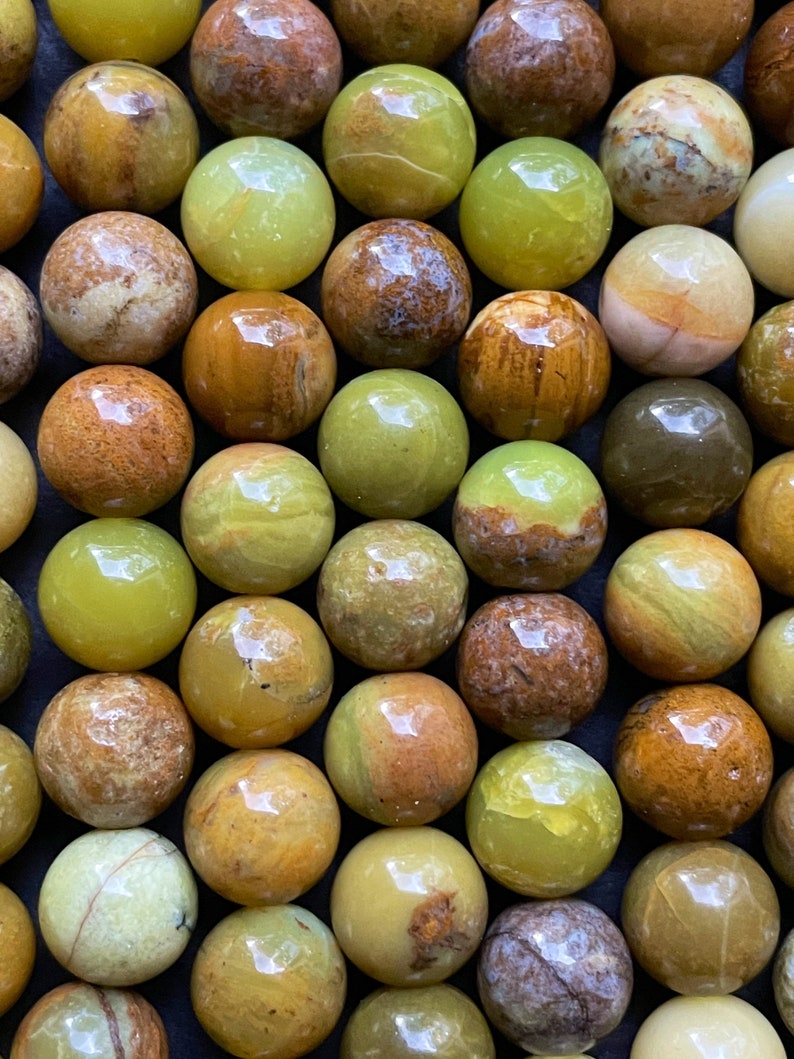 May include: A collection of green and brown opal spheres. The spheres are smooth and polished, with a variety of patterns and colors.