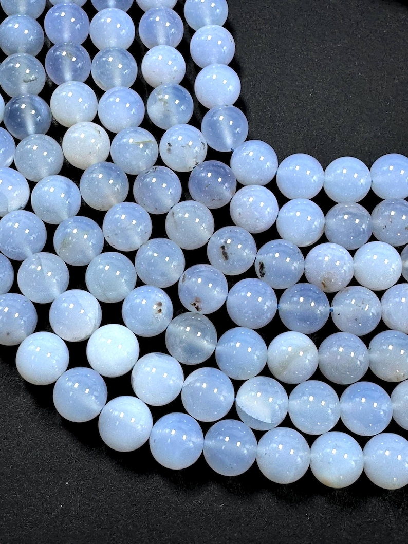 Pu&ograve; includere: Una collana di perle di agata blu chiaro. Le perle sono rotonde e lisce, con un aspetto leggermente traslucido.