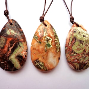 May include: Three teardrop-shaped pendants with brown leather cords. The pendants are made of a colorful, marbled stone with shades of brown, green, and white.