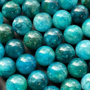 May include: A collection of teal blue and green gemstone beads. The beads are round and smooth, with a mottled appearance.