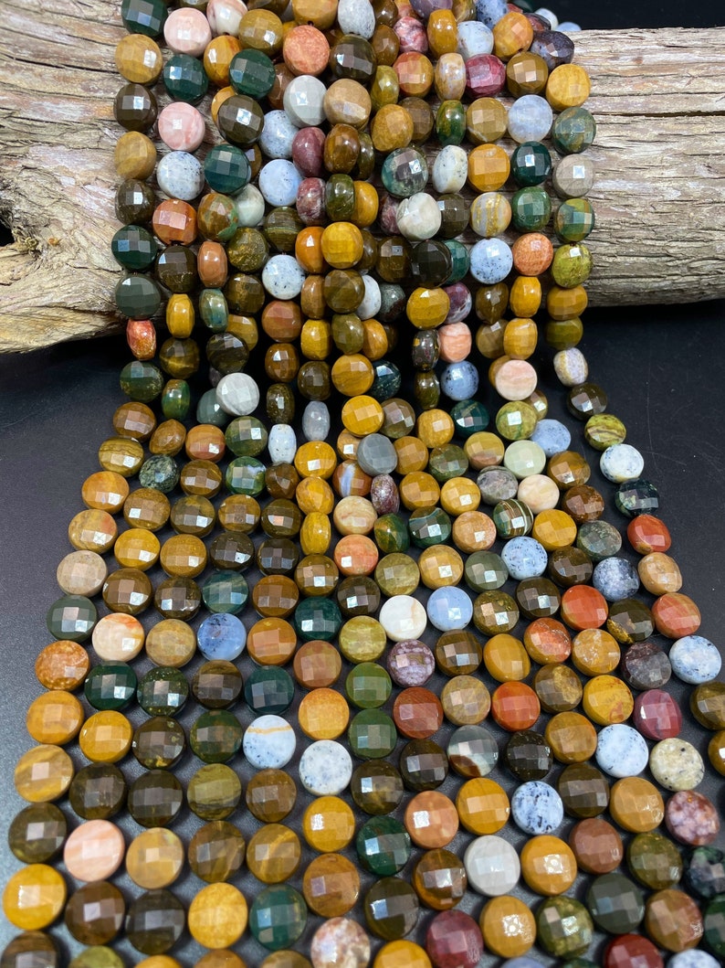 May include: A strand of multi-colored gemstone beads. The beads are round and faceted, with a variety of colors including brown, green, yellow, red, and blue. The beads are strung on a clear string.