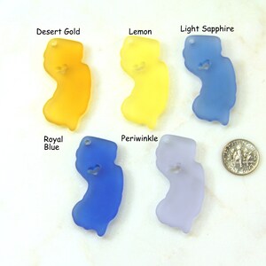 May include: Six different colored glass New Jersey state charms, in the colors desert gold, lemon, light sapphire, royal blue, periwinkle, and a US dime for scale.