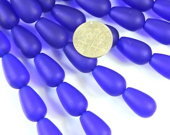 May include: A strand of deep blue glass beads in a teardrop shape. The beads are matte and have a slightly irregular shape. A US dime is included for scale.