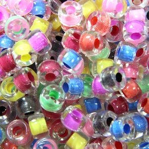 May include: A close-up of a variety of colorful plastic beads. The beads are transparent and have different colored centers. The beads are perfect for making jewelry or other crafts.