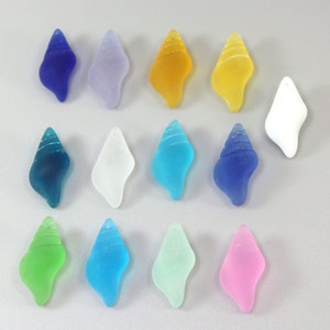 May include: Assortment of 12 sea glass shell pendants in various colors, including blue, green, pink, white, and yellow. The shells are all approximately the same size and shape, and they have a smooth, polished finish.
