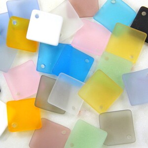 May include: Assortment of frosted glass square tiles with a hole in the corner. The tiles are in various colours, including blue, green, pink, yellow, and white.