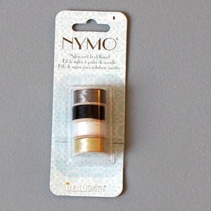 May include: A pack of NYMO nylon seed bead thread. The pack contains four spools of thread in brown, black, white, and gold.