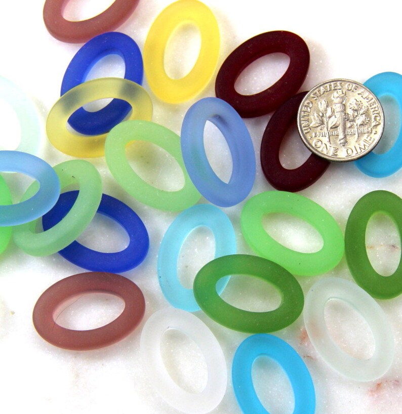 May include: Assortment of oval-shaped glass beads in various colors, including blue, green, red, yellow, and white. The beads are frosted and have a smooth, polished finish.
