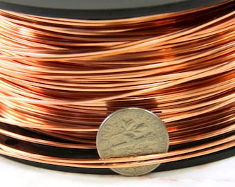 Könnte beinhalten: Eine Spule mit Kupferdraht, mit einem US-Cent als Größenvergleich. Der Draht ist fest um die Spule gewickelt und hat eine leuchtend kupferne Farbe.