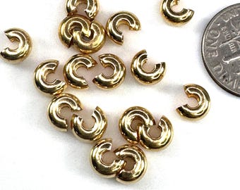 May include: A group of 14 gold-colored metal jump rings. The jump rings are about the size of a US dime.