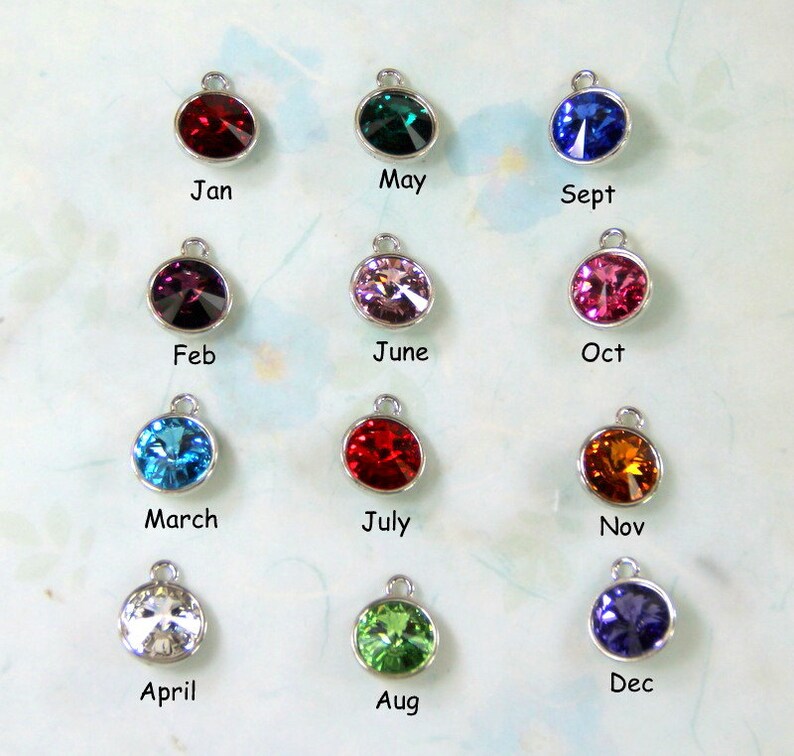 Puede incluir: Doce abalorios de plata con cristales de diferentes colores, cada uno representando un mes del a&ntilde;o. Enero es rojo, febrero es morado, marzo es azul, abril es transparente, mayo es verde, junio es rosa, julio es rojo, agosto es verde, septiembre es azul, octubre es rosa, noviembre es naranja y diciembre es morado.