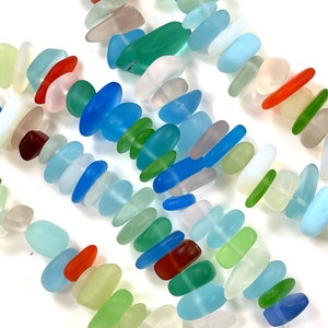May include: A strand of colorful sea glass beads, featuring shades of blue, green, red, and white. The beads are smooth and polished, with a variety of shapes and sizes.