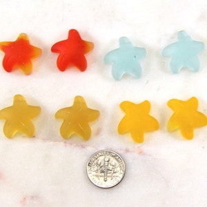 May include: Assortment of colorful gummy starfishes in yellow, orange, red, and blue. The gummy candies are arranged in two rows of four.