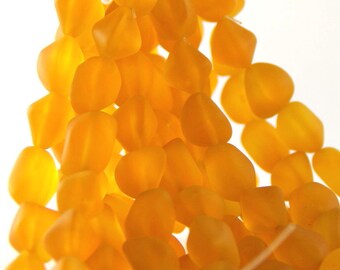 May include: Close-up of a strand of amber-coloured, irregular-shaped beads. The beads are clustered together, creating a textured and visually appealing display. The background is a bright white.
