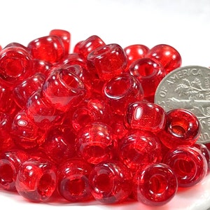 May include: A pile of bright red glass beads, some of which are translucent. The beads are about the size of a US dime.