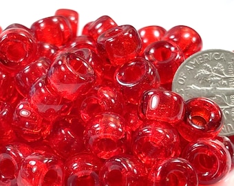 May include: A pile of bright red glass beads, some of which are translucent. The beads are about the size of a US dime.
