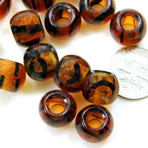 May include: A group of brown and black plastic beads with a tiger stripe pattern. The beads are about 1 inch in diameter and have a large hole in the center.