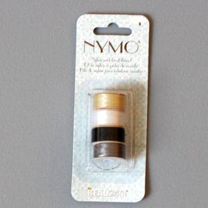 May include: A package of NYMO nylon beading thread. The package is white with blue and gold accents. The thread is in four colors: gold, white, black, and gray.