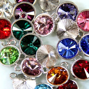 Puede incluir: Surtido de brillantes redondos de cristal de colores con engastes de metal plateado. Los brillantes son de varios colores, incluyendo rojo, verde, azul, rosa y morado.