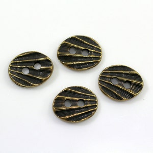 Può includere: Quattro bottoni color oro antico con un design testurizzato e nervato. Ogni bottone ha due fori.