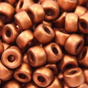May include: A close-up of a pile of copper-colored round beads. The beads are smooth and have a metallic sheen.