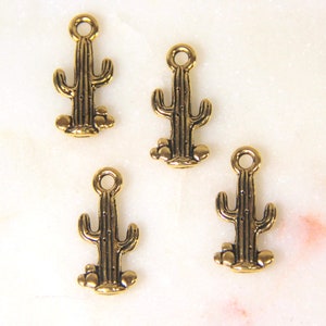May include: Four gold-colored metal cactus charms with a loop at the top for hanging. The charms are detailed with a textured cactus body and small round accents at the base.