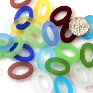 May include: Assortment of oval-shaped glass beads in various colors, including blue, green, red, yellow, and white. The beads are frosted and have a smooth, polished finish.