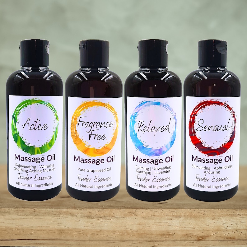 May include: Four amber glass bottles of massage oil with labels. The labels are white with a circle in the center. The circles are green, yellow, blue, and red. The text on the labels reads "Active", "Fragrance Free", "Relaxed", and "Sensual". Each label also includes the text "Massage Oil" and "Tender Essence".