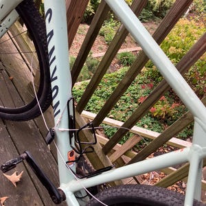 May include: A light green mountain bike with black tyres and a black handlebar. The bike is parked on a wooden deck with a railing.