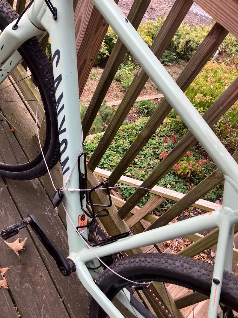 May include: A light green mountain bike with black tyres and a black handlebar. The bike is parked on a wooden deck with a railing.