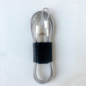 May include: A silver cable lock with a black plastic casing and the text "SureLock" printed on it.