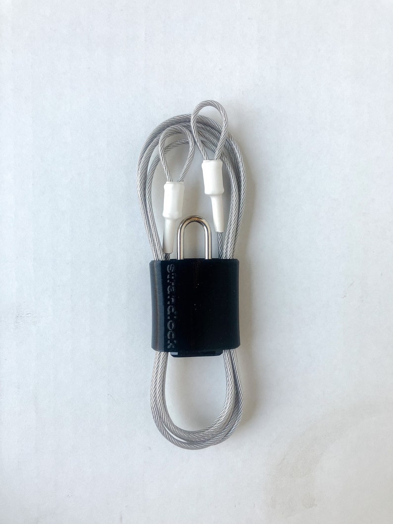 May include: A silver cable lock with a black plastic casing and the text "SureLock" printed on it.