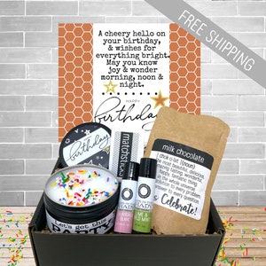 May include: A birthday gift box with a greeting card, candle, lip balms, matches, and a milk chocolate packet. The card has a honeycomb pattern and the words "Happy Birthday". The candle is decorated with colorful sprinkles.