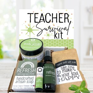 May include: A gift box labeled "Teacher Survival Kit" contains body scrub, artisan soap, bath salt soak, and other self-care items. The box includes a jar of body scrub, a bar of soap, a spray bottle, and a lip balm. The products are labeled with the words "Refresh" and "Happy".