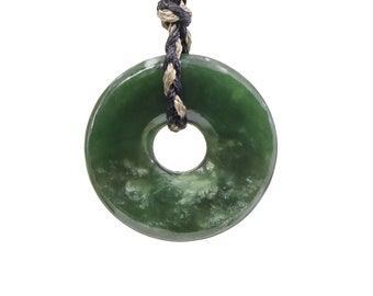 May include: A green jade pendant in the shape of a ring, hanging from a black and beige cord.
