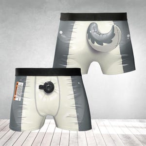 May include: Novelty boxer briefs with a shark tail design. The briefs are primarily white with gray accents and a black waistband. One pair features a shark tail graphic, while the other has a black inflation valve and a warning label.