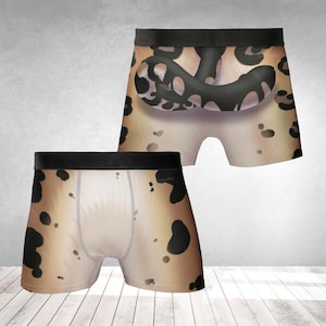 Op de afbeelding: Boxershorts met een uniek luipaardprintontwerp. Het ondergoed heeft een zwarte tailleband en een lichtbruin en zwart gevlekt patroon. De shorts worden gepresenteerd op een wit houten oppervlak.