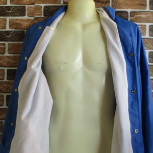 Pode incluir: Uma jaqueta azul com forro de l&atilde; branca. A jaqueta tem fecho de bot&atilde;o e gola.