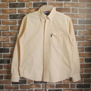 May include: A light yellow long-sleeved button-down shirt with a white stripe pattern. The shirt has a single chest pocket and a button-down collar.