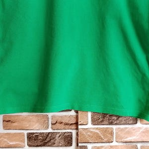 May include: A solid green long-sleeve shirt. The shirt is made of a soft material and has a crew neck. The sleeves are long and end in a cuff. The shirt is a vibrant shade of green.