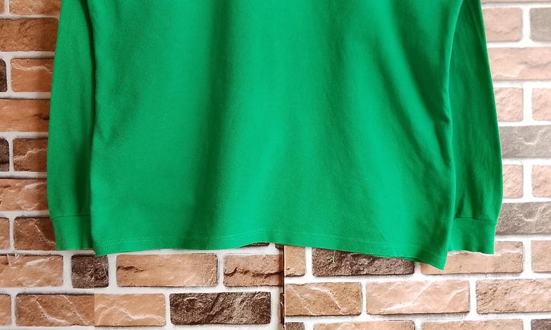 May include: A solid green long-sleeve shirt. The shirt is made of a soft material and has a crew neck. The sleeves are long and end in a cuff. The shirt is a vibrant shade of green.