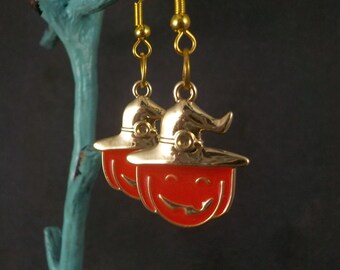 May include: A pair of gold dangle earrings with orange pumpkin faces wearing witch hats.