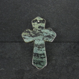May include: A green and black stone cross pendant with a silver setting.