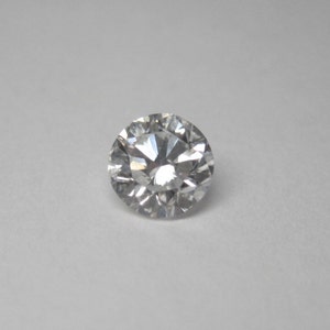 May include: A round, clear diamond gemstone with many facets.