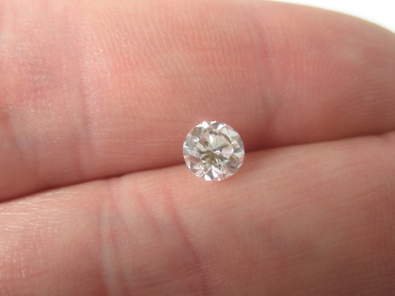 May include: A clear round diamond gemstone with facets.